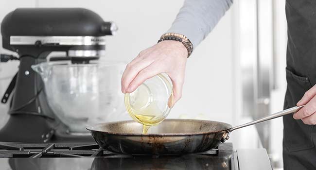 adding oil to a frying pan