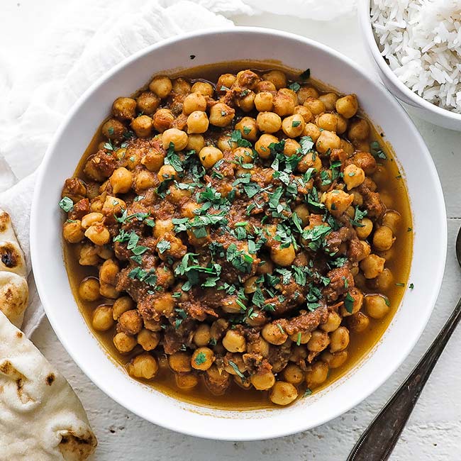 a bowl of Indian chana masala with cilantro and rice