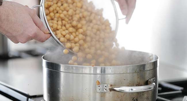 pouring drained chickpeas into a pan