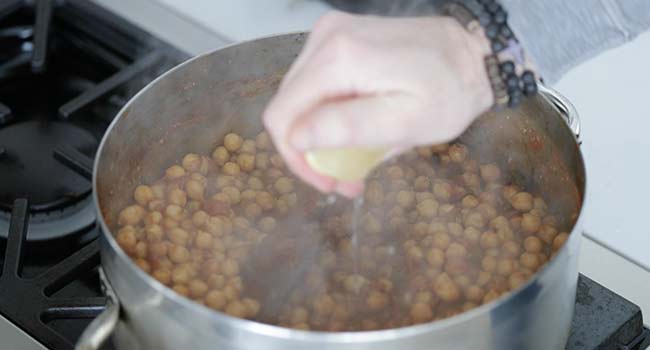 squeezing lemon juice into a chana masala