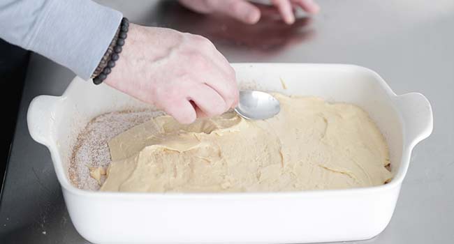 adding more batter to a cake dish