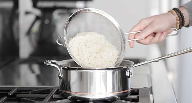 adding rinsed rice to a pot