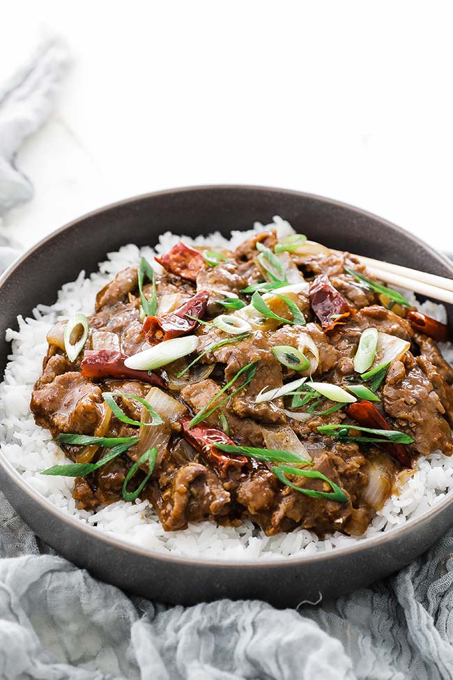 cooked mongolian beef in a bowl with green onions