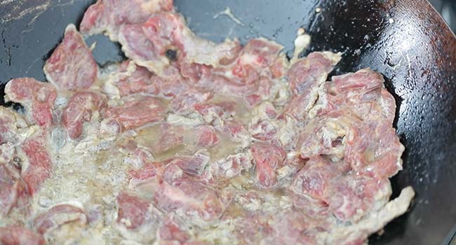 cooking sliced beef in a wok