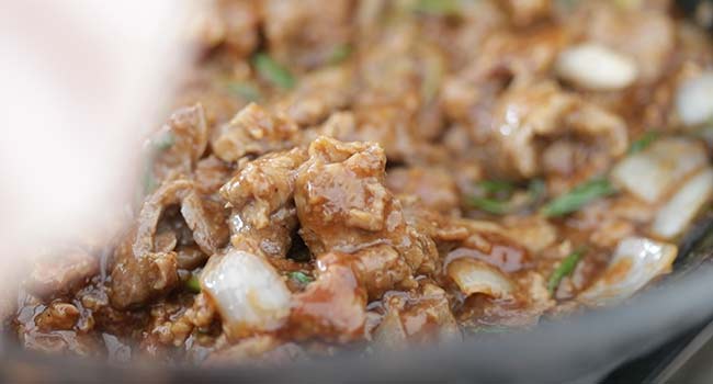 tossing cooked beef in a wok with mongolian beef