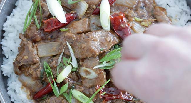 garnishing mongolian beef with sliced green onions