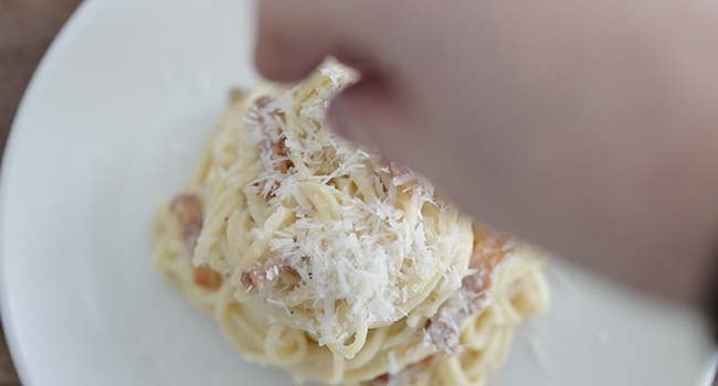 garnishing a pasta alla gricia with pecorino romano