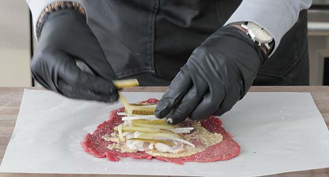 adding pickles onto a beef rouladen