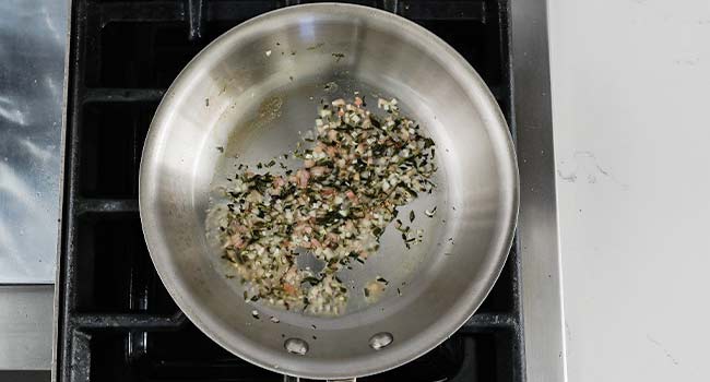 a shallot, pepper, and herb reduction in a pan