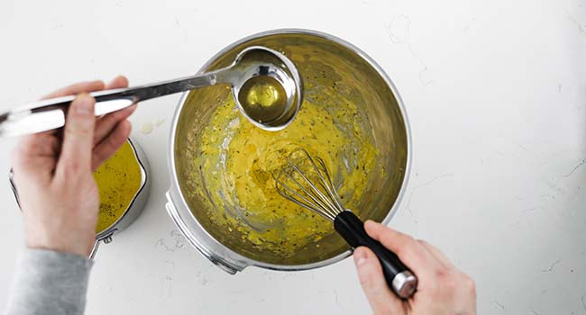 adding clarified butter to whisked egg yolks