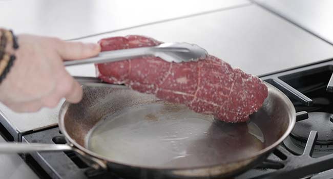searing a beef tenderloin in a pan