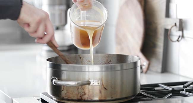 adding chicken stock to a pan with roux