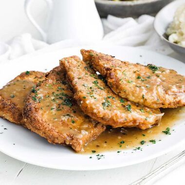 fried pork chops with gravy on a plate