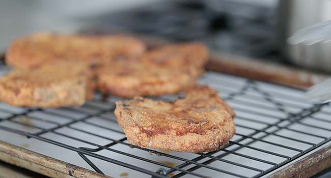 draining fried pork chops on a rack 