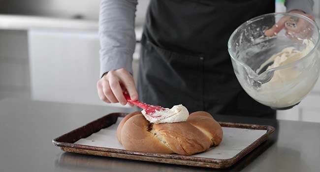 spreading frosting on a king cake