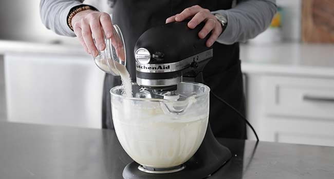 adding sugar to a stand mixer with butter