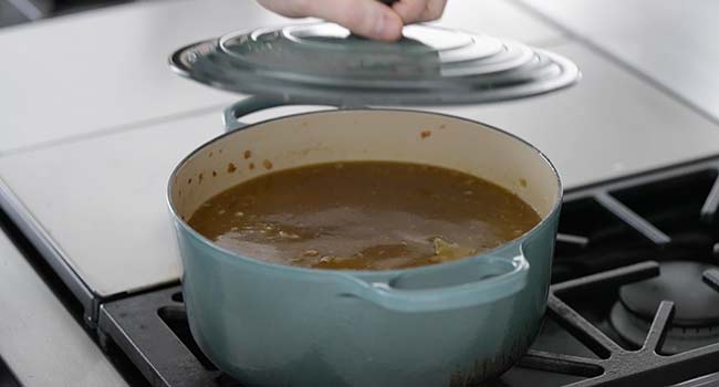 cooking a lentil soup in a pot with a lid