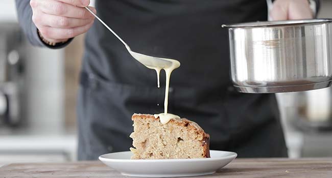 pouring vanilla custard on a slice of Irish apple cake