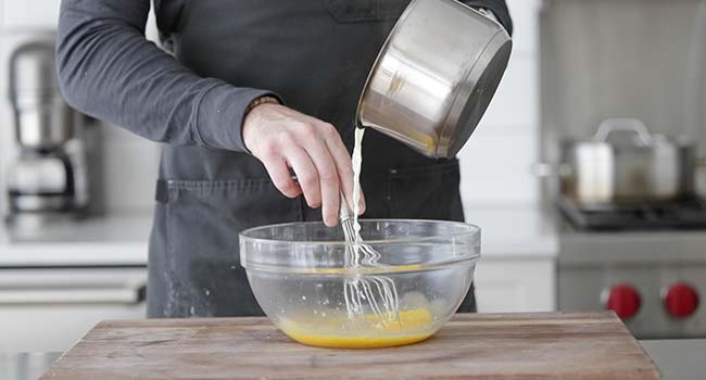 adding hot milk to egg yolks