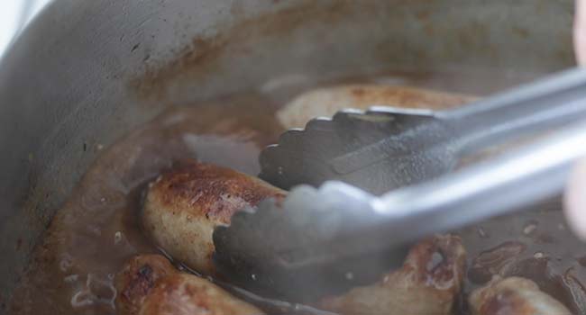 adding cooked bangers to a pot of gravy