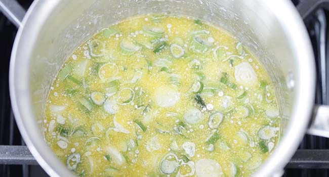 adding green onions to melted butter and milk