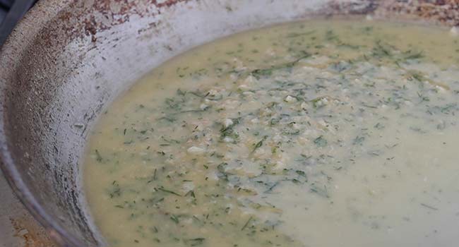 adding fresh dill to a butter sauce in a pan