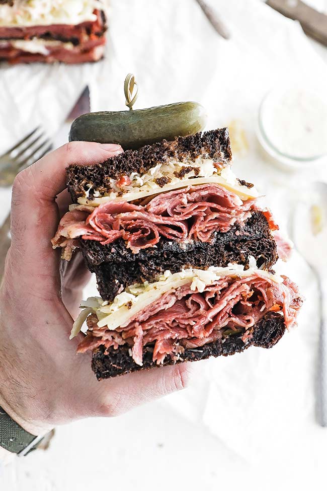 holding a sliced reuben sandwich