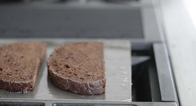 toasting some pumpernickel bread on a flat top