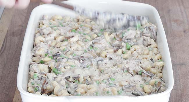 flattening out a tuna casserole in a pan