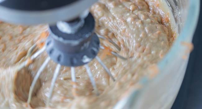 whisking shredded carrots into a batter