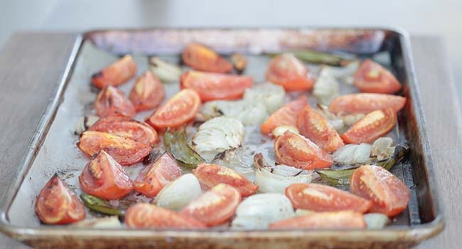 roasting tomatoes and onions on a sheet tray