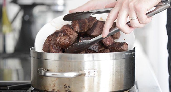 adding seared beef to a pan