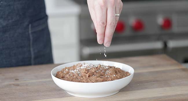 garnishing refried beans with queso fresco