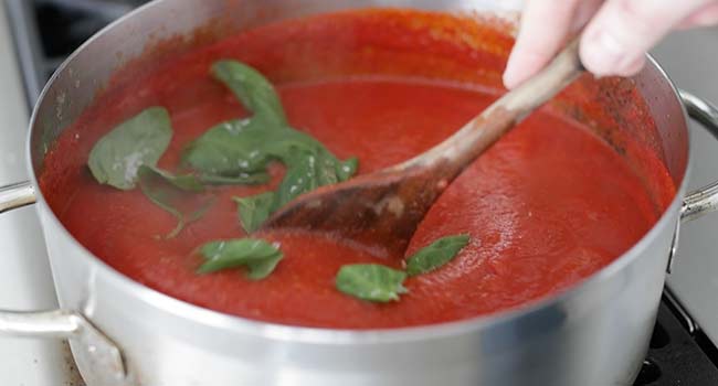 mixing basil in with pomodoro sauce