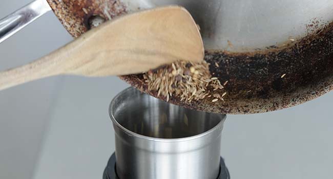 adding toasted spices to a spice grinder