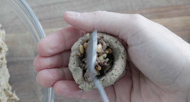 adding lamb and pine nut stuffing to the lamb casing