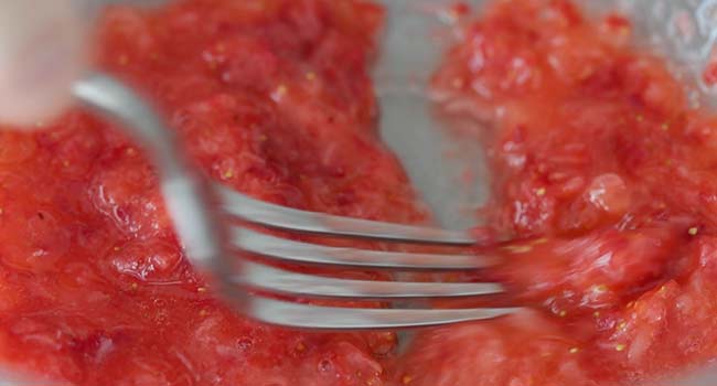 mashing strawberries with a fork