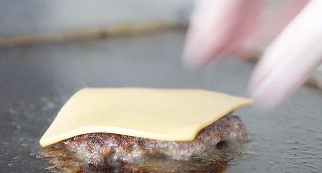 adding cheese to a smash burger