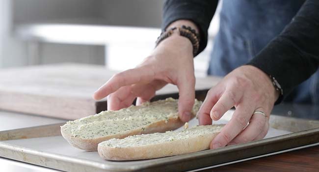 adding garlic bread to a sheet tray