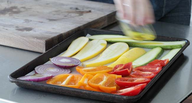 adding olive oil to a sliced vegetables