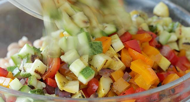 adding cooked vegetables to a bowl