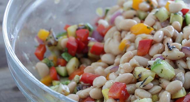 mixing a mediterranean bean salad