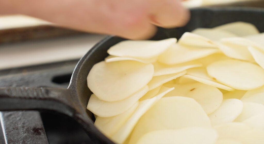 Close up of sliced potatoes in skillet 