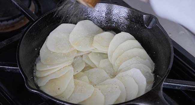 drizzling butter on sliced potatoes