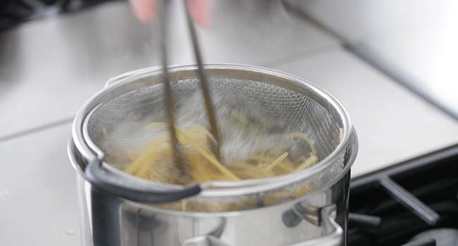 adding pasta to a pot of boiling water