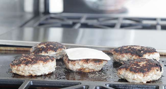 adding cheese to a turkey burger