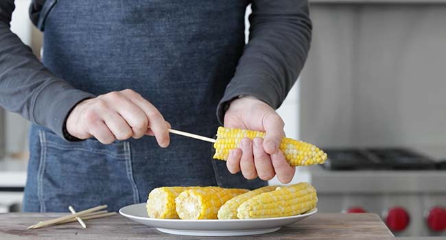 piercing corn on the cob with a wooden skewer