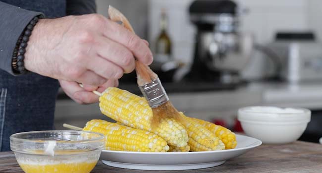 brushing corn with butter