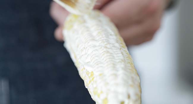 adding mayonnaise to corn