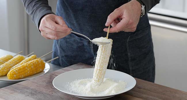 sprinkling cotija cheese on corn